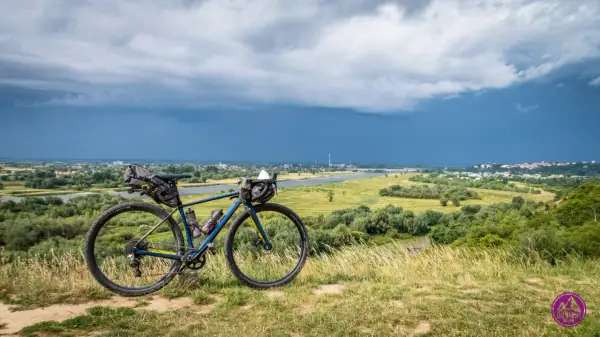 Rower gravelowy z sakwami na tle burzowego nieba nad Wisłą. Przygotowany na wyprawę Wisła 1200.