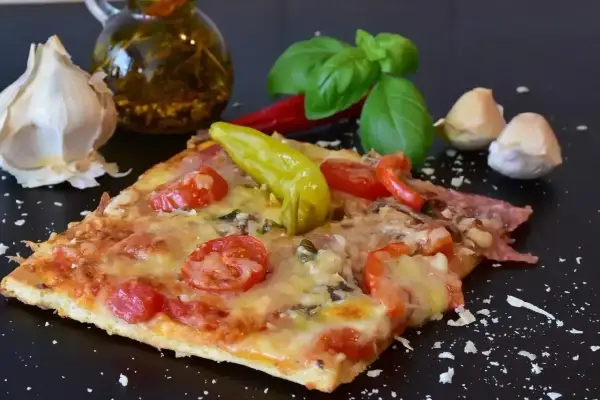 Pyszny kawałek pizzy z pomidorami i papryką, czosnkiem i bazylią. Zastanawiasz się, ile może leżeć pizza w lodówce?