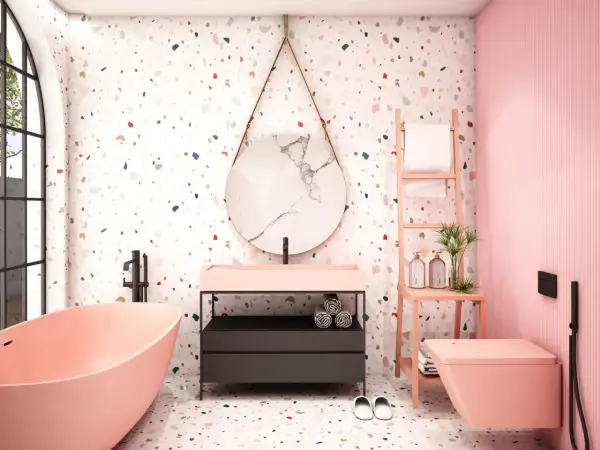 Bagno moderno con vasca rosa, lavabo, specchio rotondo e un vivace **pavimento in graniglia di marmo** multicolore.