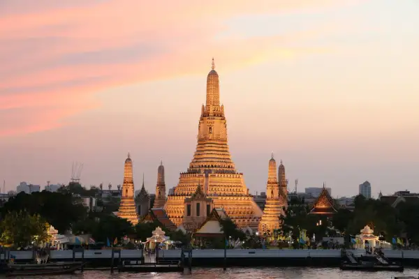 Zachód słońca nad rzeką w Bangkoku, stolicy Tajlandii pełna nazwa. Wspaniała świątynia Wat Arun rozświetlona złotym blaskiem.
