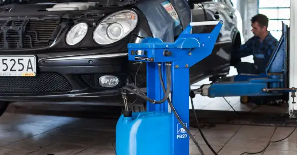 Mechanik przeprowadza wymianę płynu hamulcowego w czarnym samochodzie, używając specjalistycznego sprzętu.