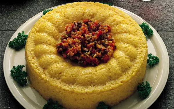 Sformatini di riso e verdure dorati, guarniti con un trito colorato e prezzemolo fresco.