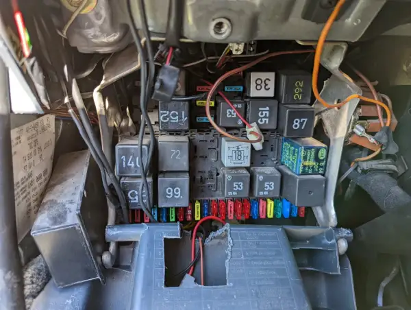 Widok na skrzynkę bezpieczników i przekaźników w samochodzie. Widać bezpiecznik od kierunkowskazu, oznaczenie 18, oraz inne elementy instalacji elektrycznej.
