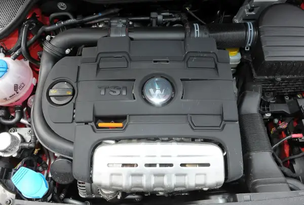 Silnik TSI w Volkswagen Polo 6R. Widoczny czarny plastikowy dekiel z logo VW i napisem TSI, a pod nim metalowa osłona.