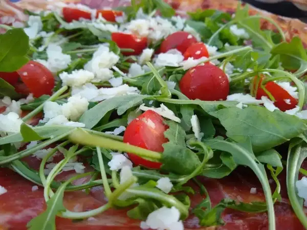 Pizza z rukolą, pomidorkami i parmezanem. Rukola właściwości zdrowotne dodają jej lekkości i świeżości.