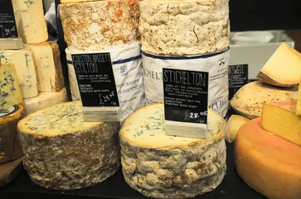 Gros plans sur des fromages anglais, dont le Stilton Colston Bassett et le Stichelton, avec leurs étiquettes de prix.