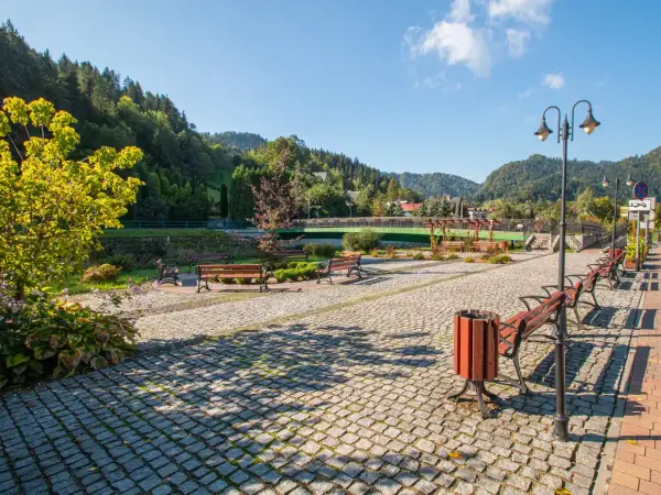 Urokliwa promenada nad Grajcarkiem, z ławkami i latarniami, zaprasza do spacerów wśród zieleni i górskiego krajobrazu.