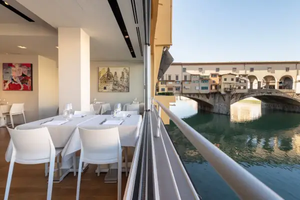 Tavoli apparecchiati con vista sul Ponte Vecchio: un'idea su dove mangiare a Firenze.