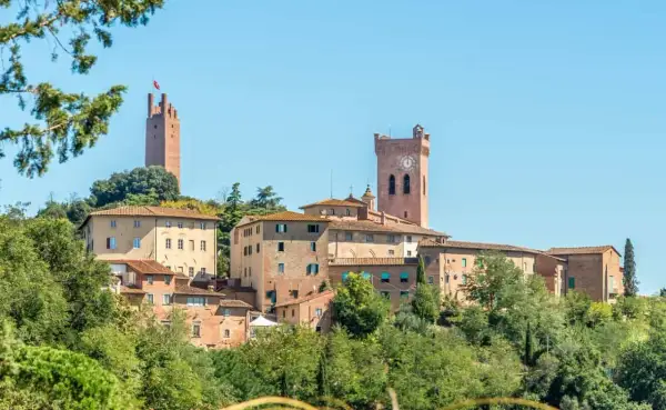 Borgo medievale di San Miniato con torri imponenti e case in pietra, immerso nel verde della campagna toscana.