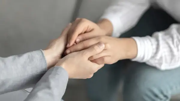 Dłonie splatają się w geście wsparcia, próbując przełamać apatię i przywrócić nadzieję.