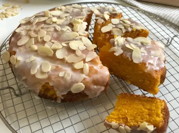 Torta carote mandorle e cioccolato, soffice e profumata, ricoperta da glassa e mandorle a lamelle.