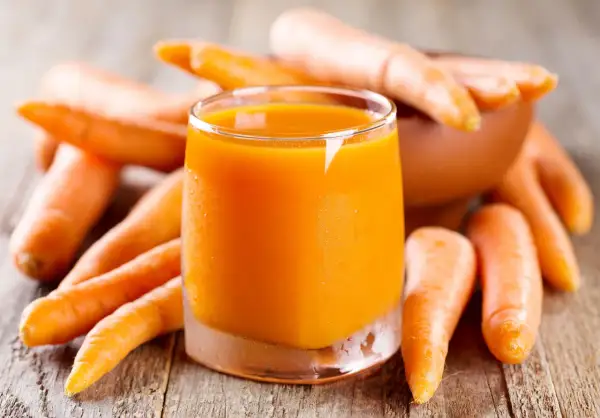 Succo d'arancia brillante circondato da carote fresche, un concentrato di vitamine e benefici per la salute.