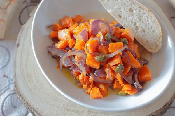 Zucca in padella con cipolle rosse e capperi, un contorno saporito servito con pane fresco.