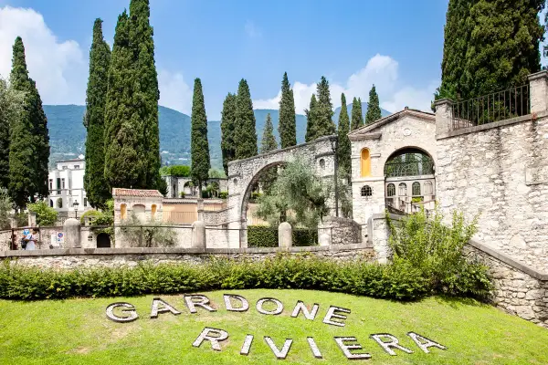 Giardini del Vittoriale, con cipressi svettanti, architetture in pietra e il nome "Gardone Riviera" sull'erba. Ecco cosa vedere al Vittoriale.