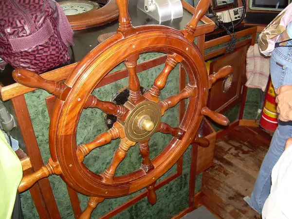Il timone, come si chiama il volante della nave, è di legno lucido, pronto a guidare.