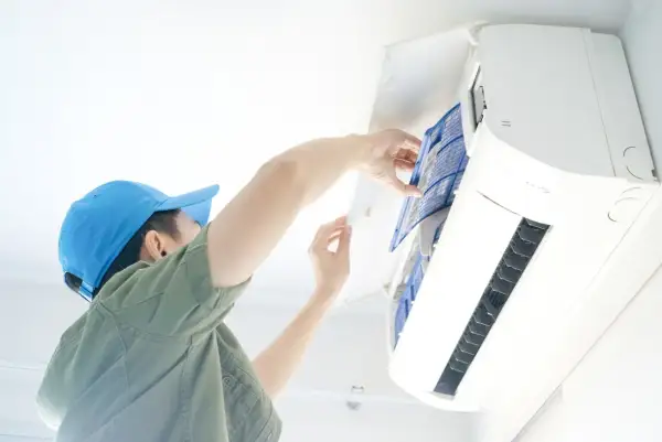Un technicien nettoie le filtre d'une climatisation, une obligation pour le bailleur afin d'assurer le confort et la qualité de l'air.