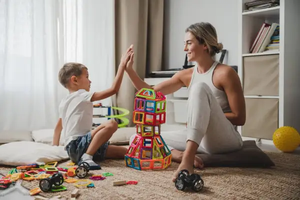 Mama i syn budują wieżę z klocków, ciesząc się wspólnymi zabawami na 3 osoby w domu.
