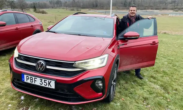 Man med halsduk vid en röd VW Taigo. Bilen är redo för ett vw taigo test i svensk natur.