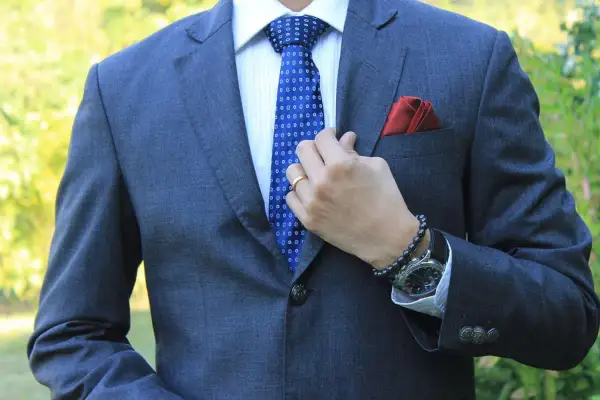 Mann im grauen Anzug mit blauer Krawatte, die perfekt zu seinem blauen Anzug passt. Rotes Einstecktuch.