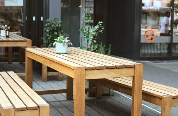 Ensemble de mobilier d'extérieur en bois, table et bancs, dont le traitement met en valeur la beauté naturelle du bois.