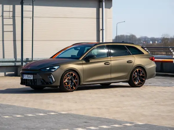 Złoty Cupra Leon Kombi z miedzianymi akcentami na felgach i dachu, zaparkowany na zewnątrz.