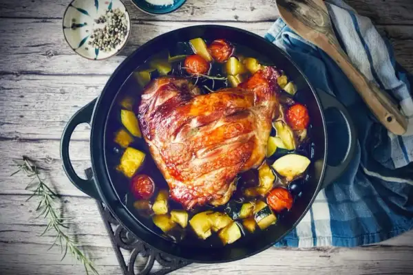 Knusprige putenoberkeule im Bräter mit Gemüse, Tomaten und Kräutern.