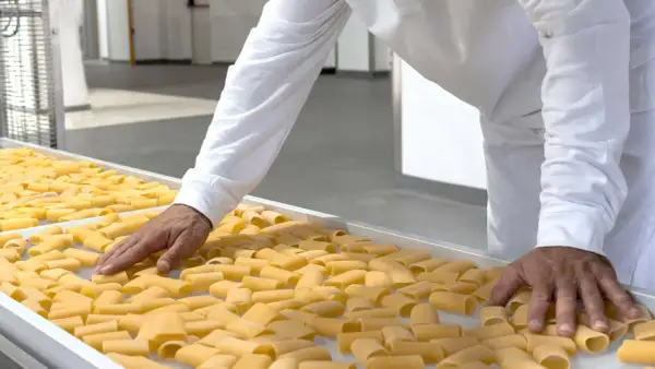 Mani che controllano paccheri freschi, pronti per le migliori cavedano ricette.