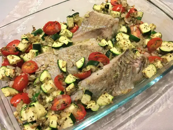 Filet de lieu noir rôti avec tomates cerises et courgettes coupées en dés, assaisonné d'herbes.