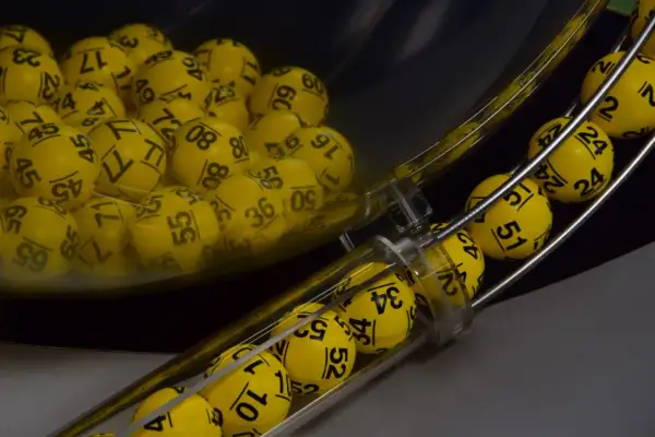 Żółte kulki z numerami w maszynie losującej, które wyłonią zwycięzców gry Eurojackpot.