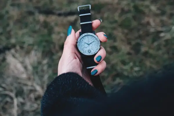 Dłoń z turkusowymi paznokciami trzyma zegarek z czarną bransoletką. Zastanawiasz się, czym wyczyścić bransoletkę od zegarka?