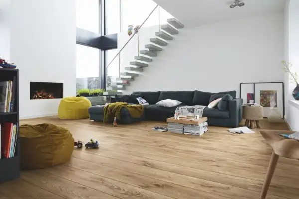 Salon moderne avec canapé, cheminée, poufs et escalier flottant. Le parquet flottant, d'une épaisseur idéale, réchauffe l'espace.