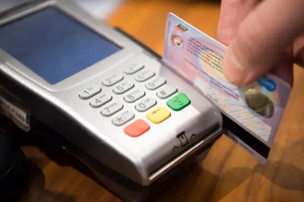 Zbliżenie na terminal płatniczy, gdzie ręka wsuwa kartę. Szybki zwrot na kartę z terminala ile trwa?