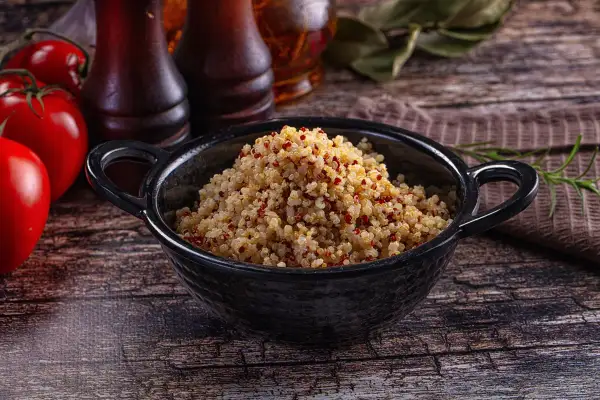 Quinoa cotta in una ciotola nera, pronta per essere gustata. Ecco come cuocere la quinoa per un piatto sano e gustoso.