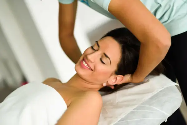 Donna sorride durante una seduta di terapia cranio sacrale. Non si segnalano effetti collaterali negativi, solo benessere.