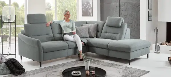 Frau liest auf einem gemütlichen Ecksofa mit verstellbaren Kopfstützen. Die tiefe **sitztiefe sofa** lädt zum Entspannen ein.