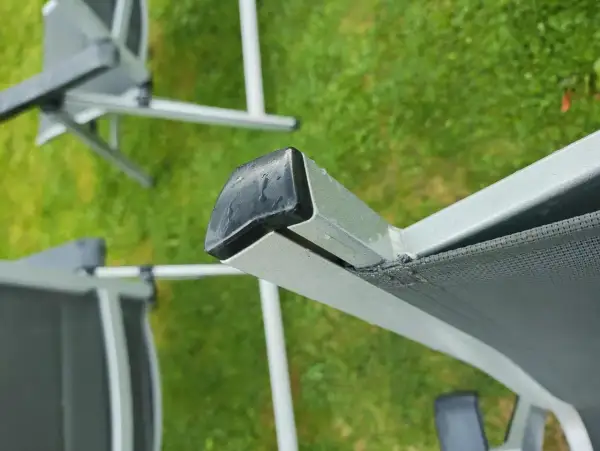 Nahaufnahme eines beschädigten Gartenstuhl PVC Bespannung. Die Reparatur ist dringend nötig, um den Stuhl wieder nutzbar zu machen.