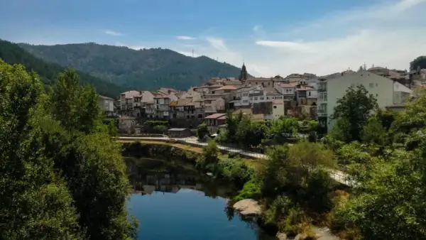 Un pueblo con tejados rojos y casas blancas se alza sobre un río tranquilo. Un lugar perfecto para descubrir qué ver en Ribadavia.