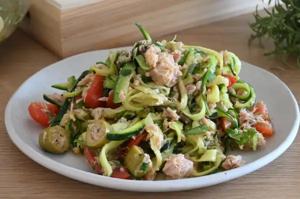 Deliziosa insalata di zucchine crude a spirale con tonno, pomodorini e olive verdi. Un piatto fresco e leggero.