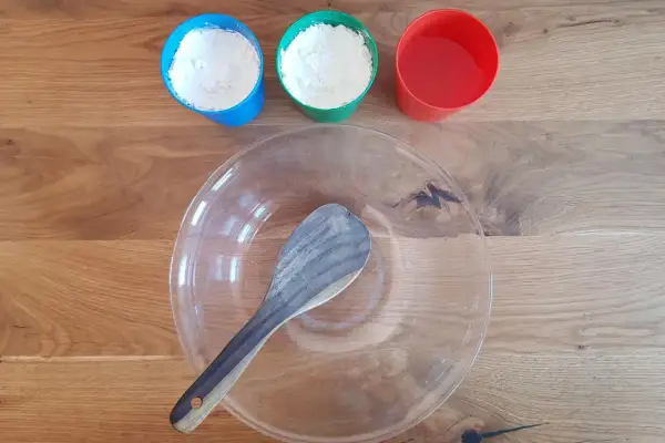 Zutaten für das Oobleck-Rezept: Mehl in blauen und grünen Bechern, Wasser im roten Becher und eine Schüssel mit Löffel.