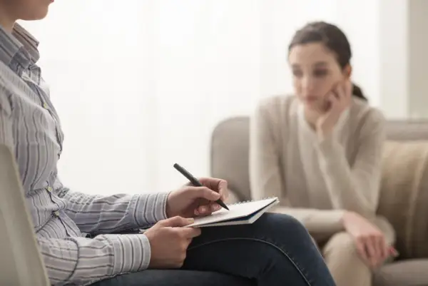 Psycholog notuje podczas sesji. Zastanawiasz się, ile zarabia psycholog? To zależy od doświadczenia i specjalizacji.