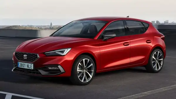 Czerwony Seat Leon, auto pochodzenia hiszpańskiego, zaparkowany na tle miasta.