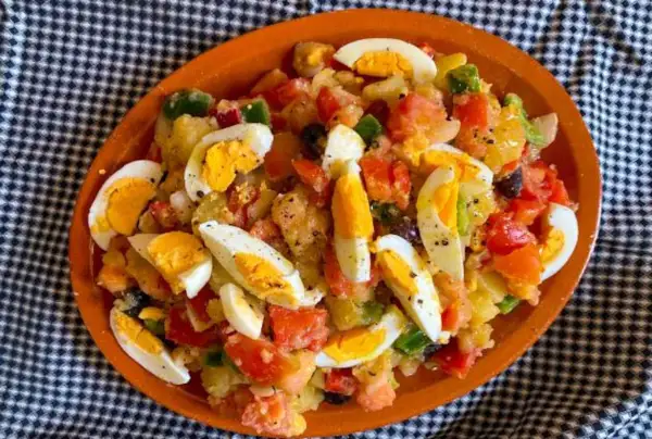 Deliciosa ensalada de patatas de verano con huevos duros, tomates, pimientos y aceitunas.
