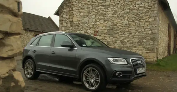 Szary Audi Q5 Quattro zaparkowany przy kamiennym budynku.