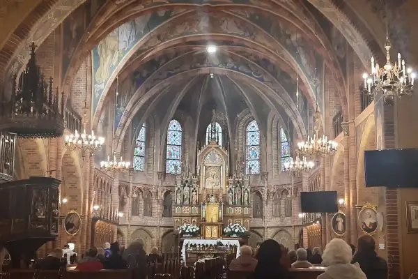 Wnętrze bazyliki z ołtarzem, gdzie króluje Matka Boska Gietrzwałdzka. Witraże i malowidła zdobią sklepienie.