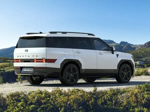 Biały Hyundai Santa Fe 2025 z czarnymi felgami na tle górskiego krajobrazu.