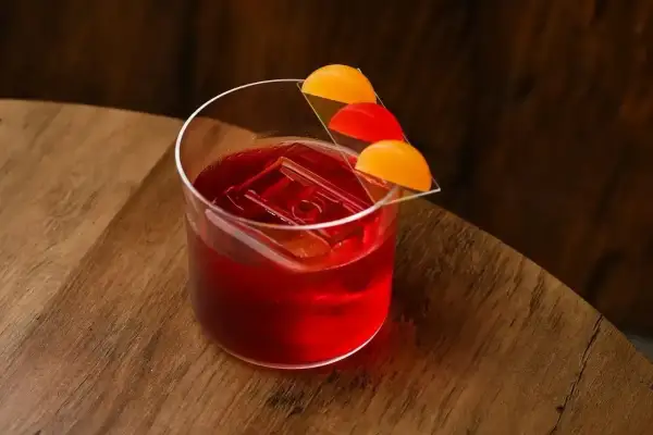 Elegancki negroni sklad z lodem i pomarańczową dekoracją na drewnianym blacie.
