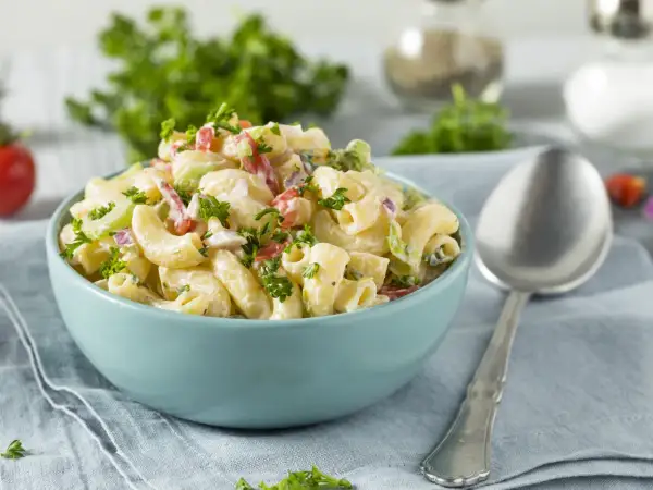 Cremiger Nudelsalat mit Joghurt, garniert mit frischer Petersilie. Perfekt für ein leichtes Mittagessen.