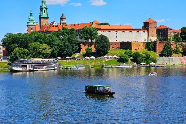 Krakau Sightseeing: Wawel-Schloss thront über dem Fluss mit Booten, die vorbeifahren.