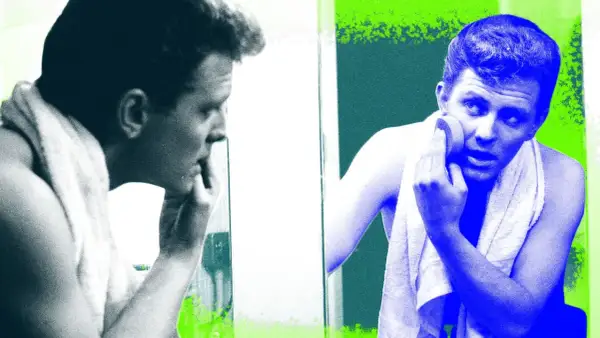 Visage homme 40 ans, se regardant dans le miroir, une serviette sur les épaules, appliquant un produit sur sa peau.