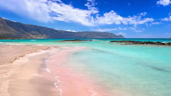 Różowa plaża z turkusową wodą i górami w tle – to jedna z najpiękniejszych plaż na świecie.